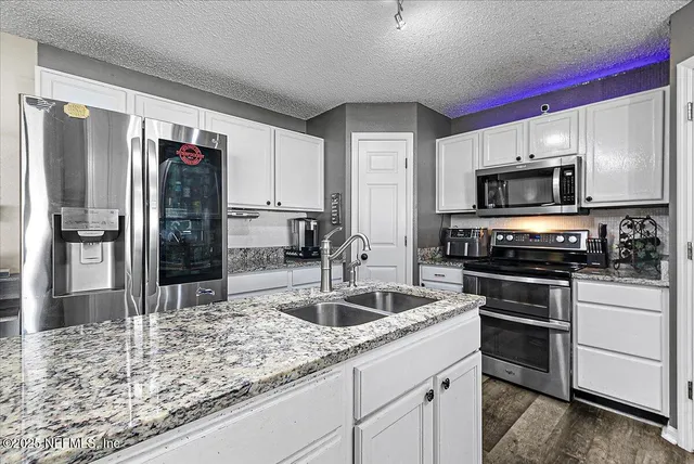 a kitchen with stainless steel appliances granite countertop a refrigerator and a sink