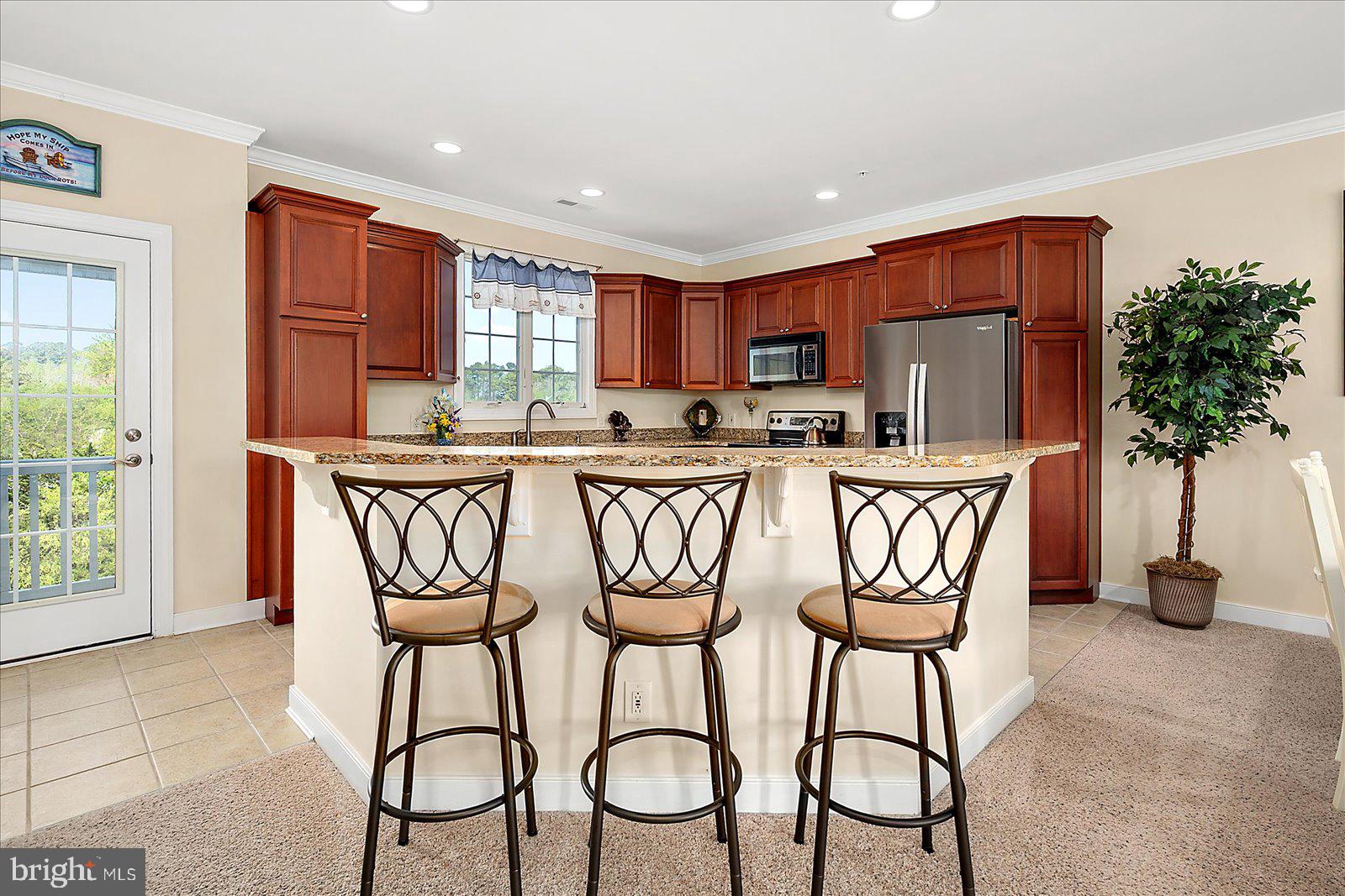 9823 Golf Course Road, Unit 7 Ocean City, MD 21842 - Photo 19 of 76 a kitchen with stainless steel appliances granite countertop a table chairs and a refrigerator