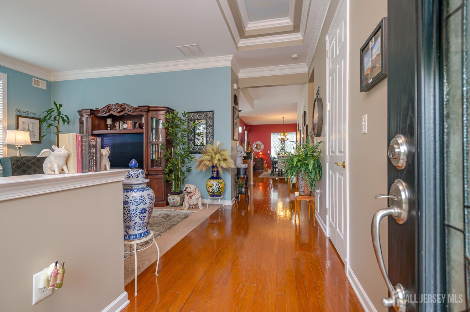44 Kings Mill Road Monroe Township, NJ 08831 - Photo 6 of 38 a hallway with a dining table wooden floor and a chandelier