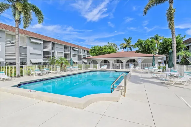 a view of house with swimming pool outdoor seating and covered with trees