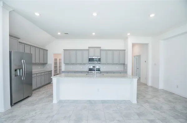 a view of a kitchen with kitchen island a sink stainless steel appliances and cabinets