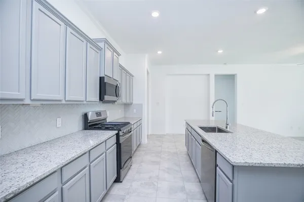 a kitchen with stainless steel appliances granite countertop a sink dishwasher stove and refrigerator