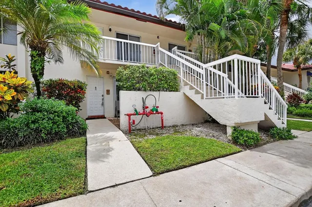 a view of a house with a yard plants and large tree