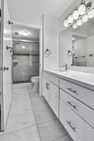a spacious bathroom with a granite countertop sink a toilet and a mirror