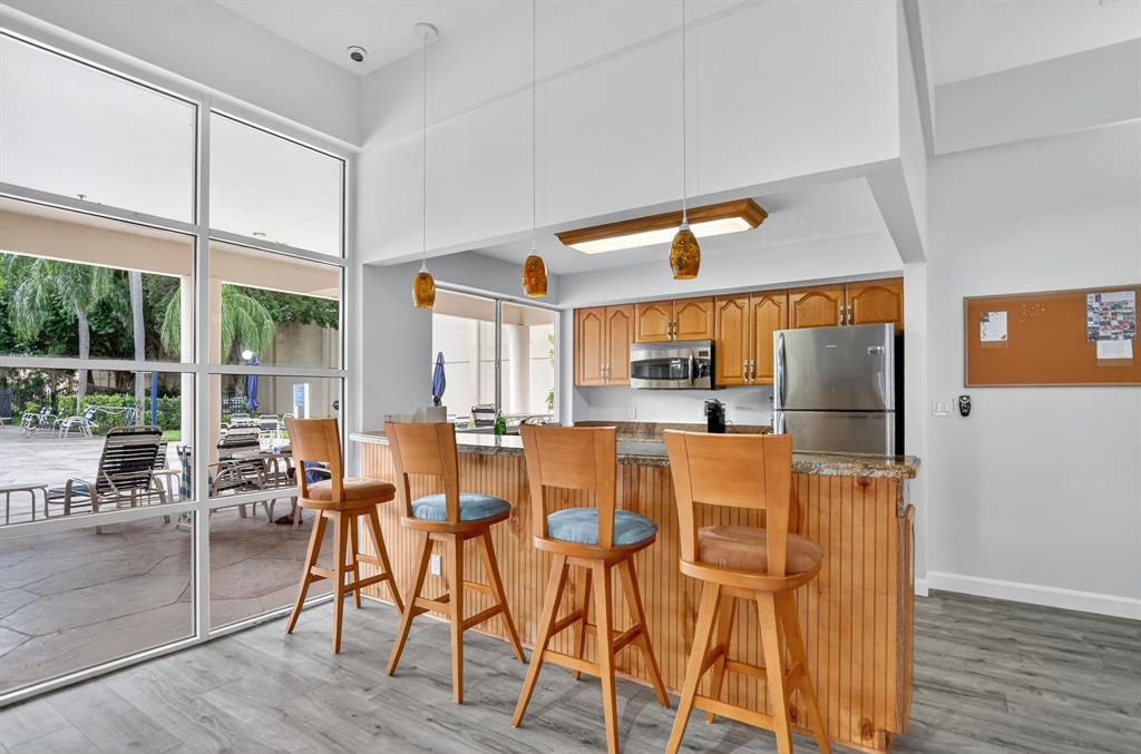 260 Northwest 67th Street, Unit A104 Boca Raton, FL 33487 - Photo 37 of 43 a dining room with furniture a floor to ceiling window and wooden floor