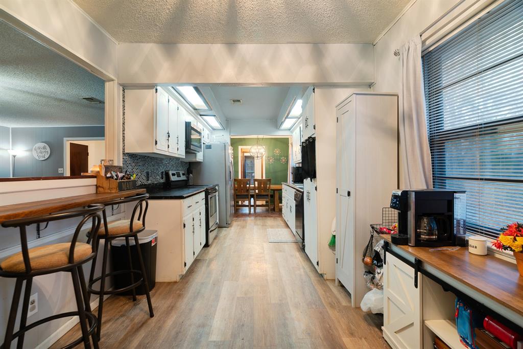 333 County Road Powderly, TX 75473 - Photo 14 of 15 a kitchen with stainless steel appliances a stove a refrigerator a sink dishwasher and a stove with wooden floor