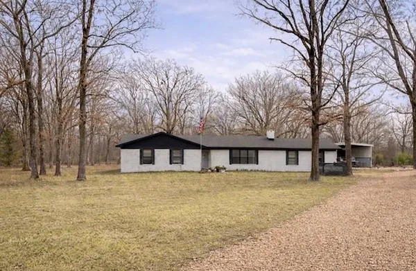 a large white house with a large tree covered with snow in front of house