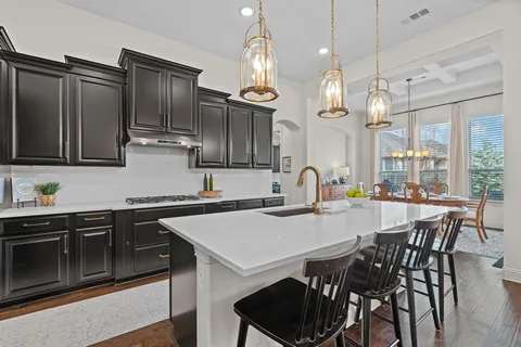 a kitchen with stainless steel appliances a table chairs sink and stove top oven
