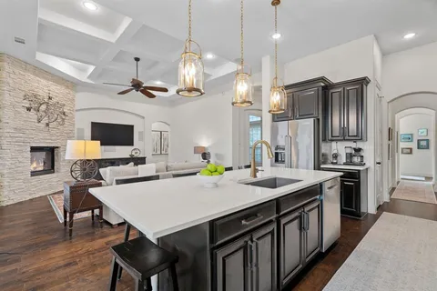 a kitchen with stainless steel appliances granite countertop a stove a refrigerator a kitchen island a sink dishwasher and white cabinets with wooden floor