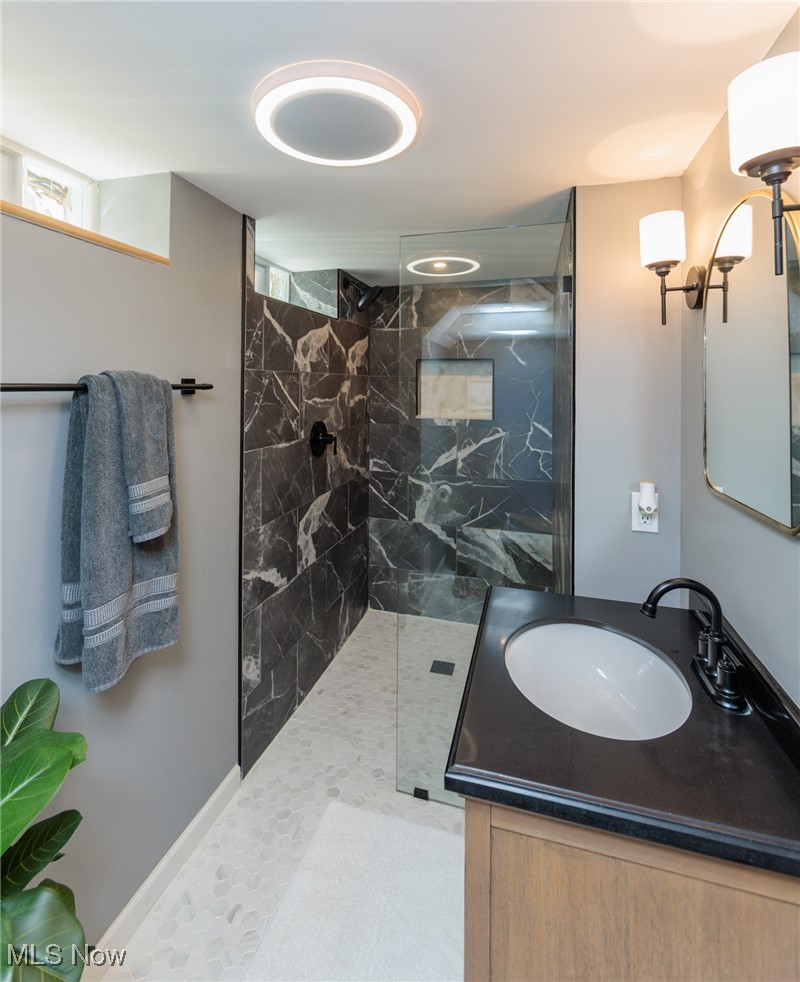 7316 Oakwood Road Parma, OH 44130 - Photo 27 of 41 Bathroom featuring a marble finish walk-in shower, vanity, and light tile patterned floors