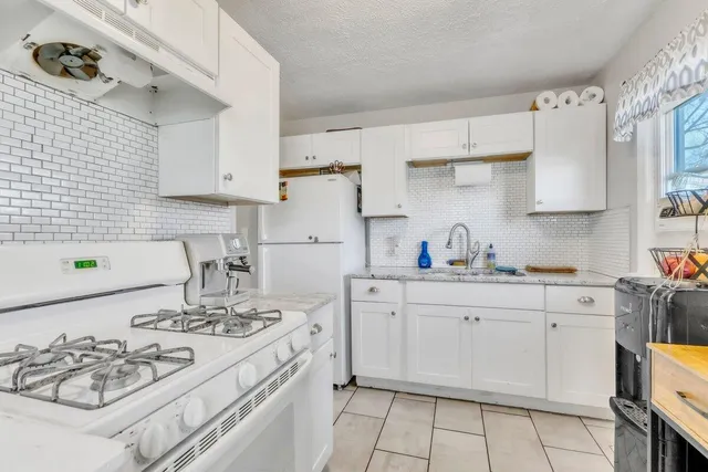a kitchen with white cabinets a stove a sink and a stove