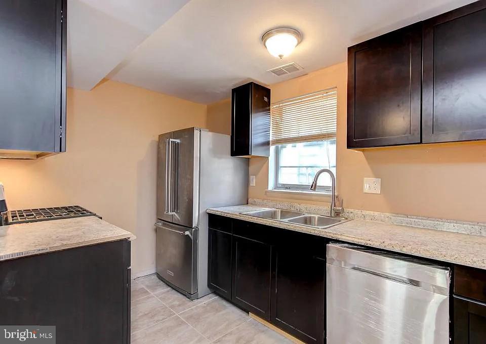 1309 East Madison Street Baltimore, MD 21205 - Photo 7 of 20 a kitchen with stainless steel appliances granite countertop a sink and a refrigerator
