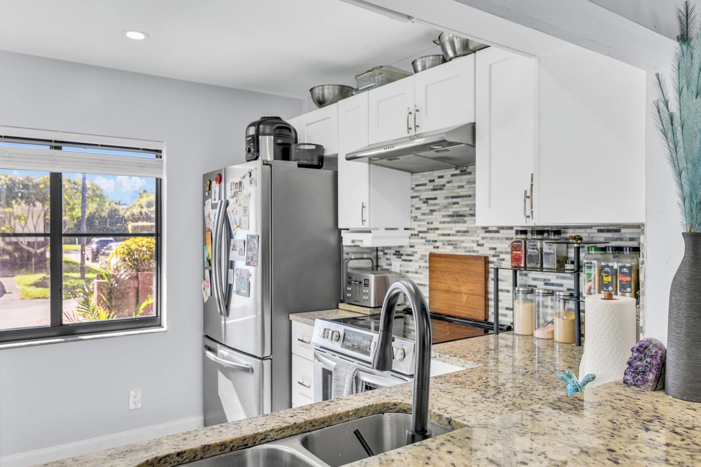 5347 Tennis Lane, Unit 5347 Delray Beach, FL 33484 - Photo 13 of 41 a kitchen with stainless steel appliances granite countertop a refrigerator and a stove