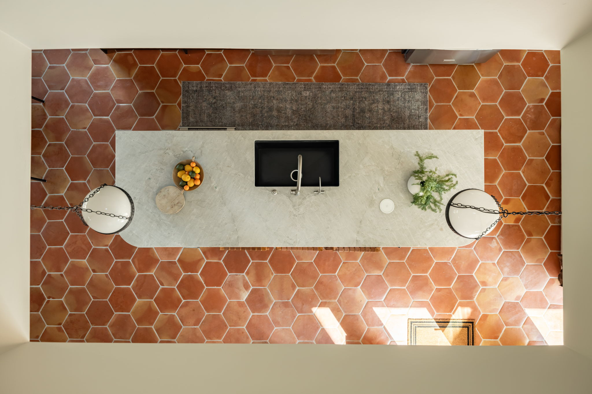 4713 Bolm Road Austin, TX 78702 - Photo 23 of 40 Kitchen featuring hexagonal terracotta floor tiles, a light-toned island with an integrated sink, and two spherical pendant lights with chain suspension