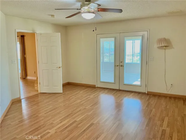 a view of an empty room with wooden floor and a ceiling fan