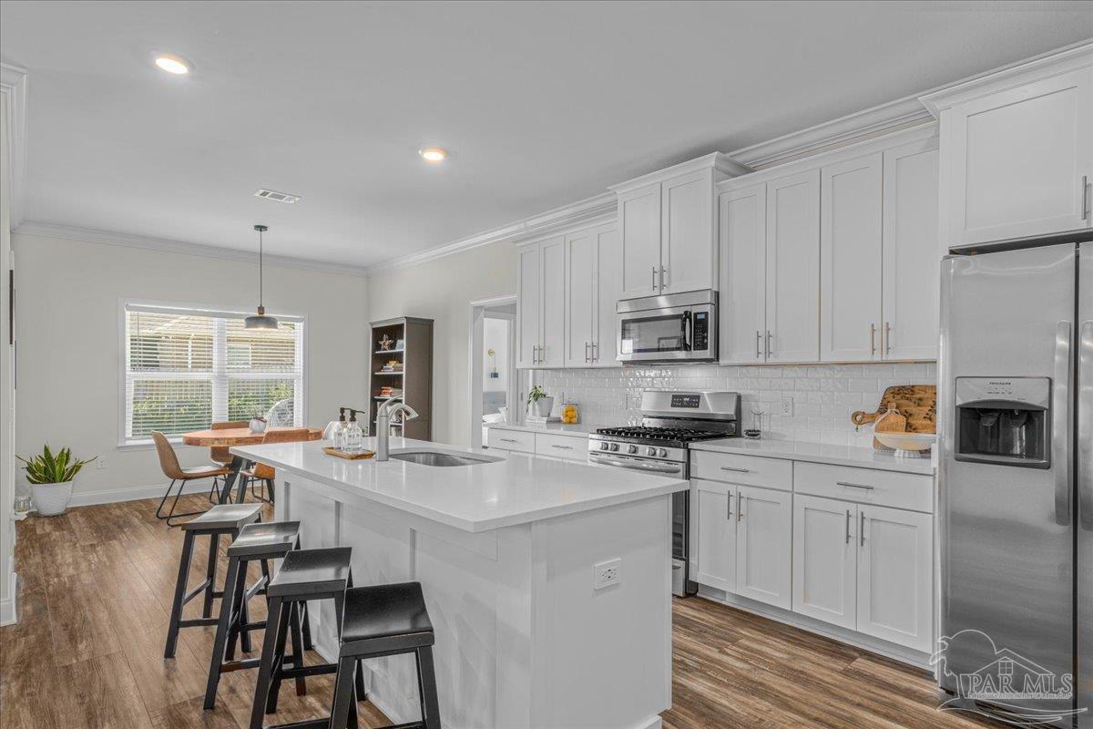 441 Broadleaf Circle Cantonment, FL 32533 - Photo 14 of 42 a kitchen with stainless steel appliances a white table chairs and a refrigerator