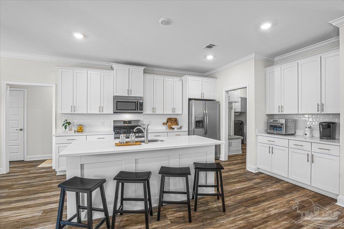 441 Broadleaf Circle Cantonment, FL 32533 - Photo 16 of 42 a kitchen with stainless steel appliances a table chairs refrigerator and cabinets