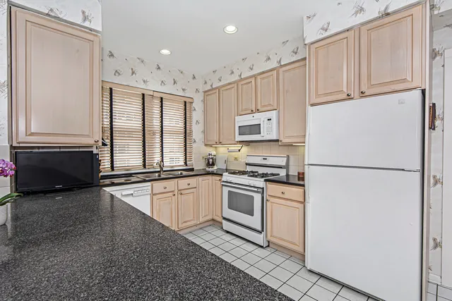 a kitchen with granite countertop white cabinets and white appliances