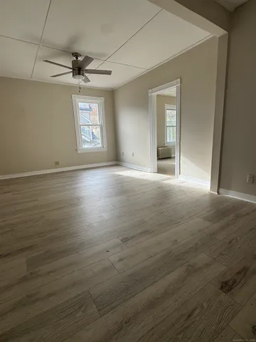 an empty room with wooden floor fan and windows