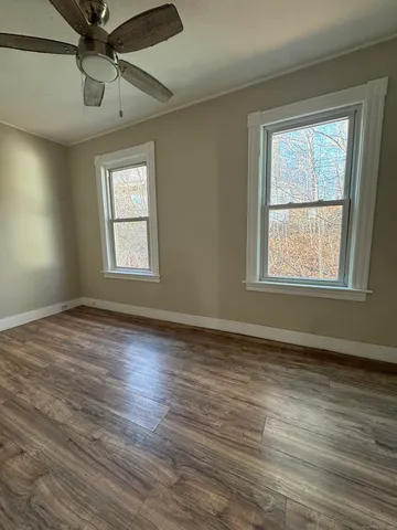 a view of an empty room with wooden floor and a window