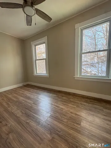 a view of an empty room with wooden floor and a window
