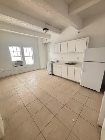 a large white kitchen with a stove a sink dishwasher and a refrigerator with white cabinets