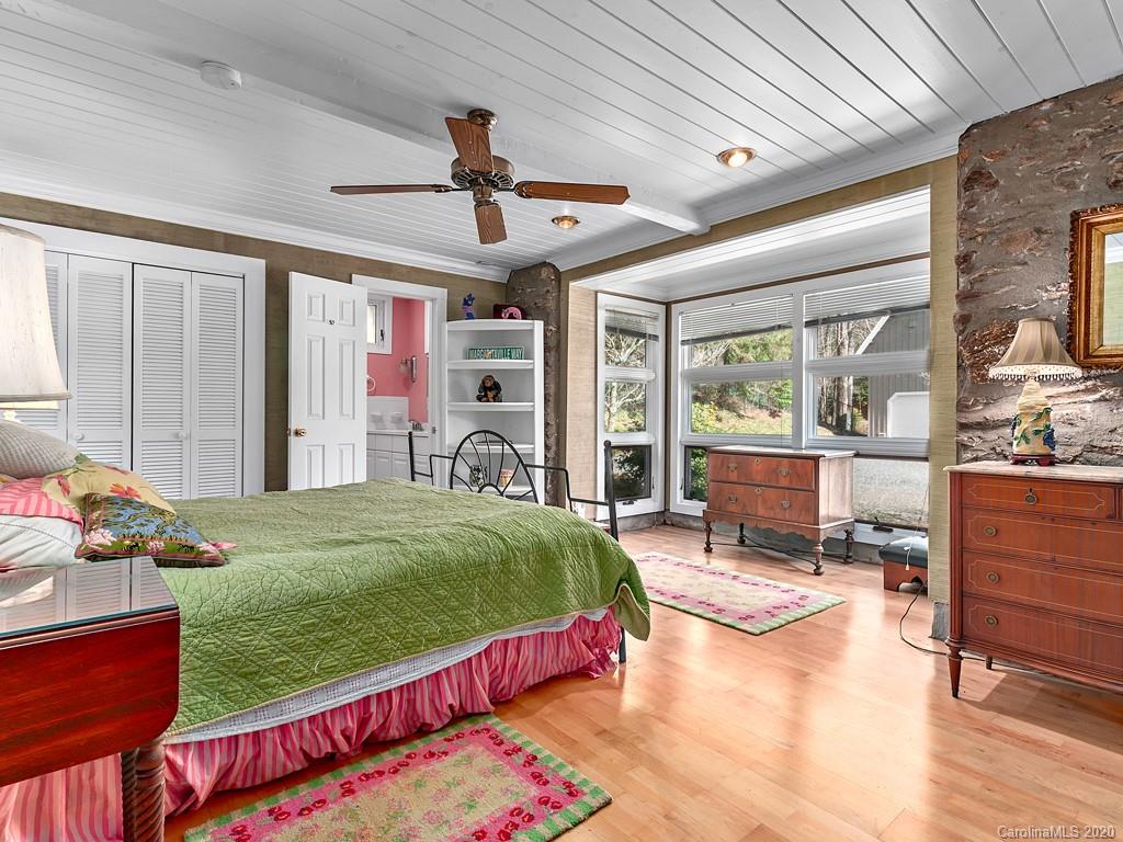 950 Walker Road Waynesville, NC 28786 - Photo 16 of 29 a bed room with a bed mirror and a ceiling fan