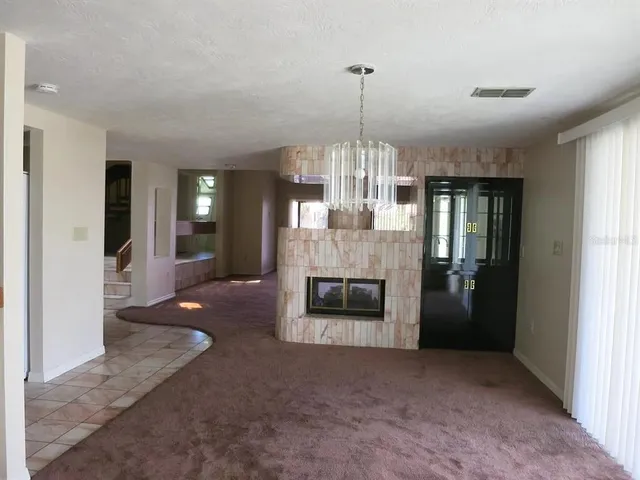 a view of a livingroom with a fireplace a chandelier and windows