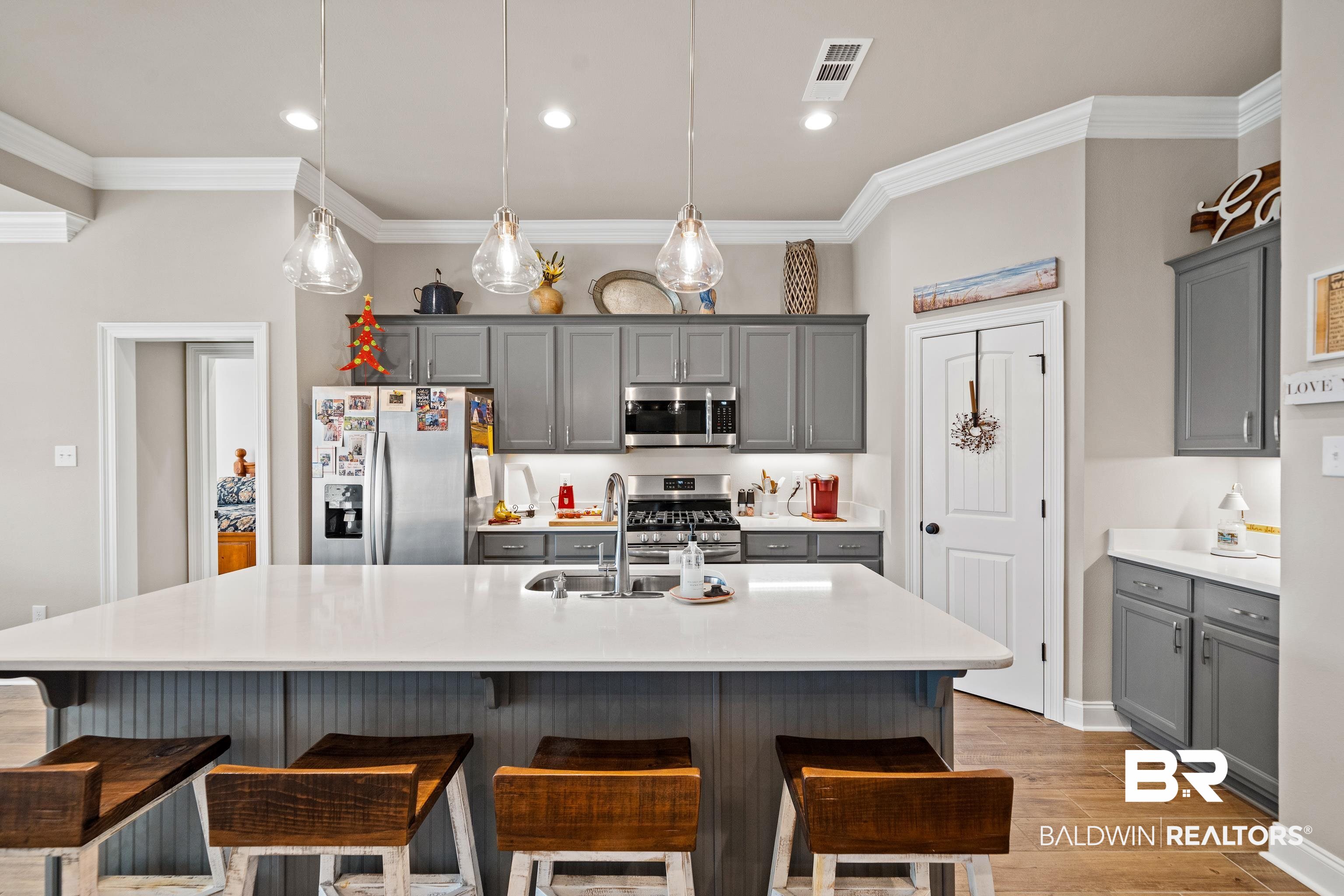 1390 Aldon Street Foley, AL 36535 - Photo 6 of 31 Kitchen with gray cabinets, a kitchen breakfast bar, stainless steel appliances, a center island with sink, and ornamental molding
