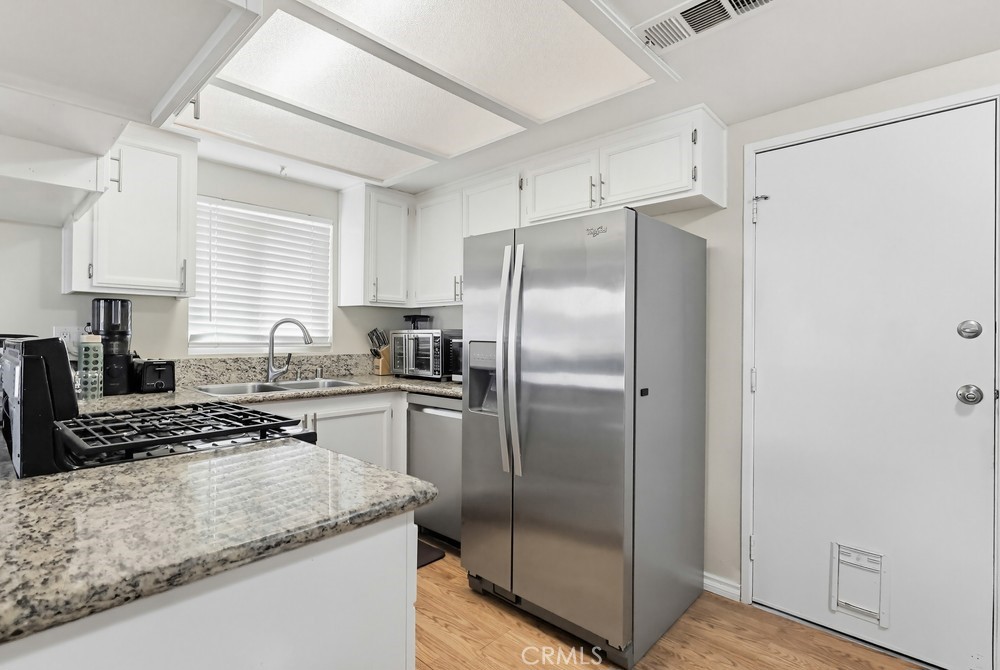 13470 Meyer Road, Unit 22 Whittier, CA 90605 - Photo 14 of 50 a kitchen with stainless steel appliances granite countertop a refrigerator a stove a sink and white cabinets