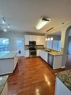 an empty room with wooden floor a fireplace and windows