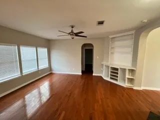 a view of an empty room with a window and wooden floor