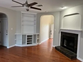 an empty room with wooden floor fireplace and windows