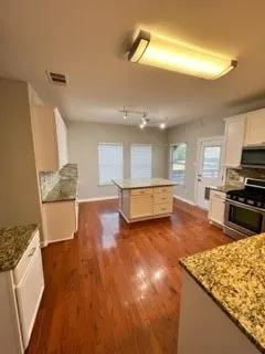 a large kitchen with stainless steel appliances kitchen island granite countertop a large stove a sink dishwasher and a stove with wooden floor