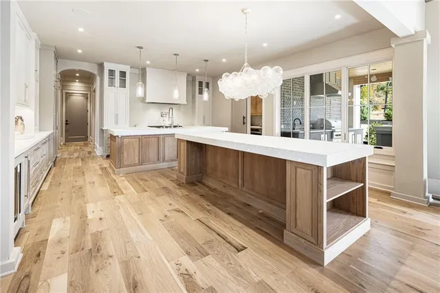 a view of an empty room with wooden floor and a ceiling fan