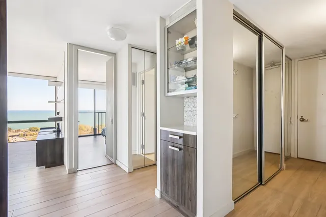 a view of a hallway with wooden floor and a bathroom
