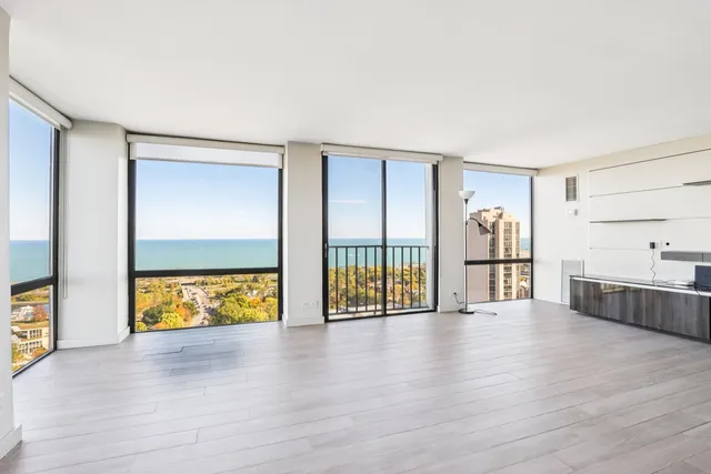 a view of an empty room with window and wooden floor