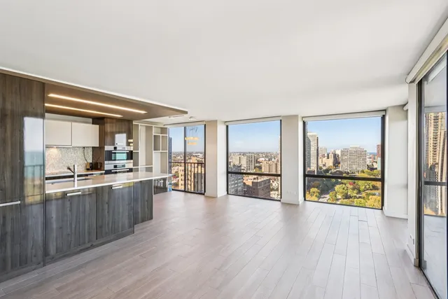 a large living room with kitchen view and wooden floor