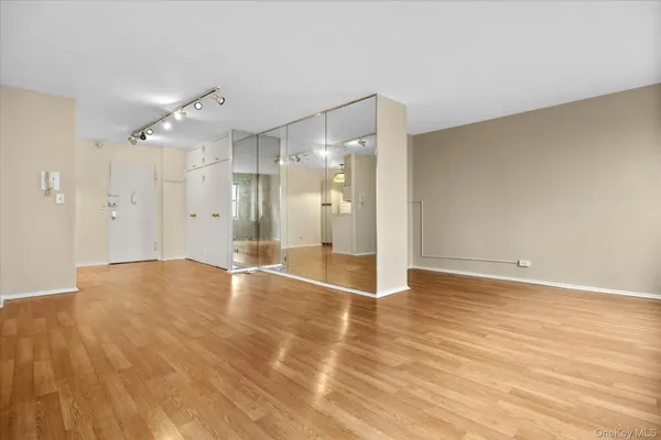 a view of an empty room with wooden floor and a bathroom