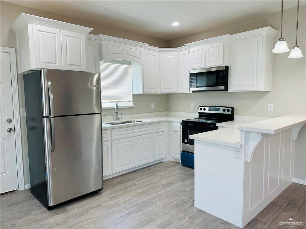 1614 Playa Drive, Unit 2 Weslaco, TX 78596 - Photo 2 of 8 a kitchen with a refrigerator a microwave a sink and cabinets