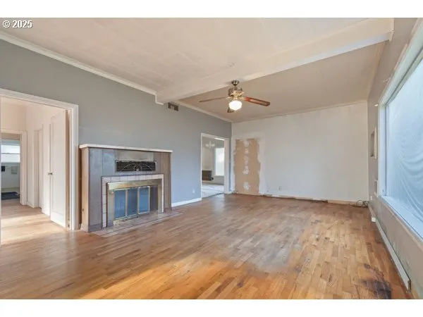 a view of an empty room with window and wooden floor