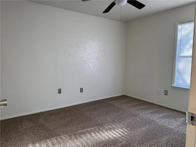 an empty room with a window and a chandelier fan