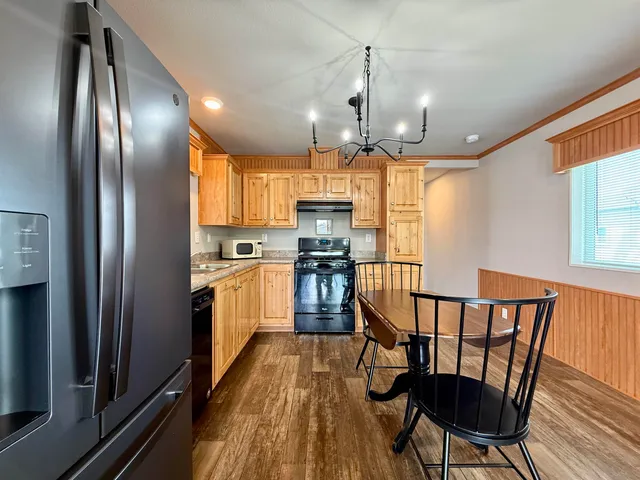 a kitchen with granite countertop stainless steel appliances a dining table chairs refrigerator and sink