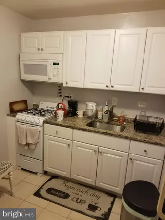 a kitchen with granite countertop white cabinets and white appliances