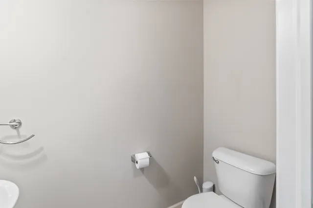 a white toilet sitting next to a white wall