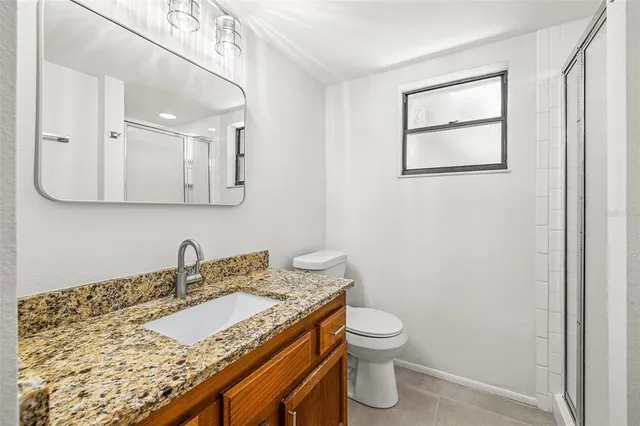 a bathroom with a granite countertop sink and a toilet