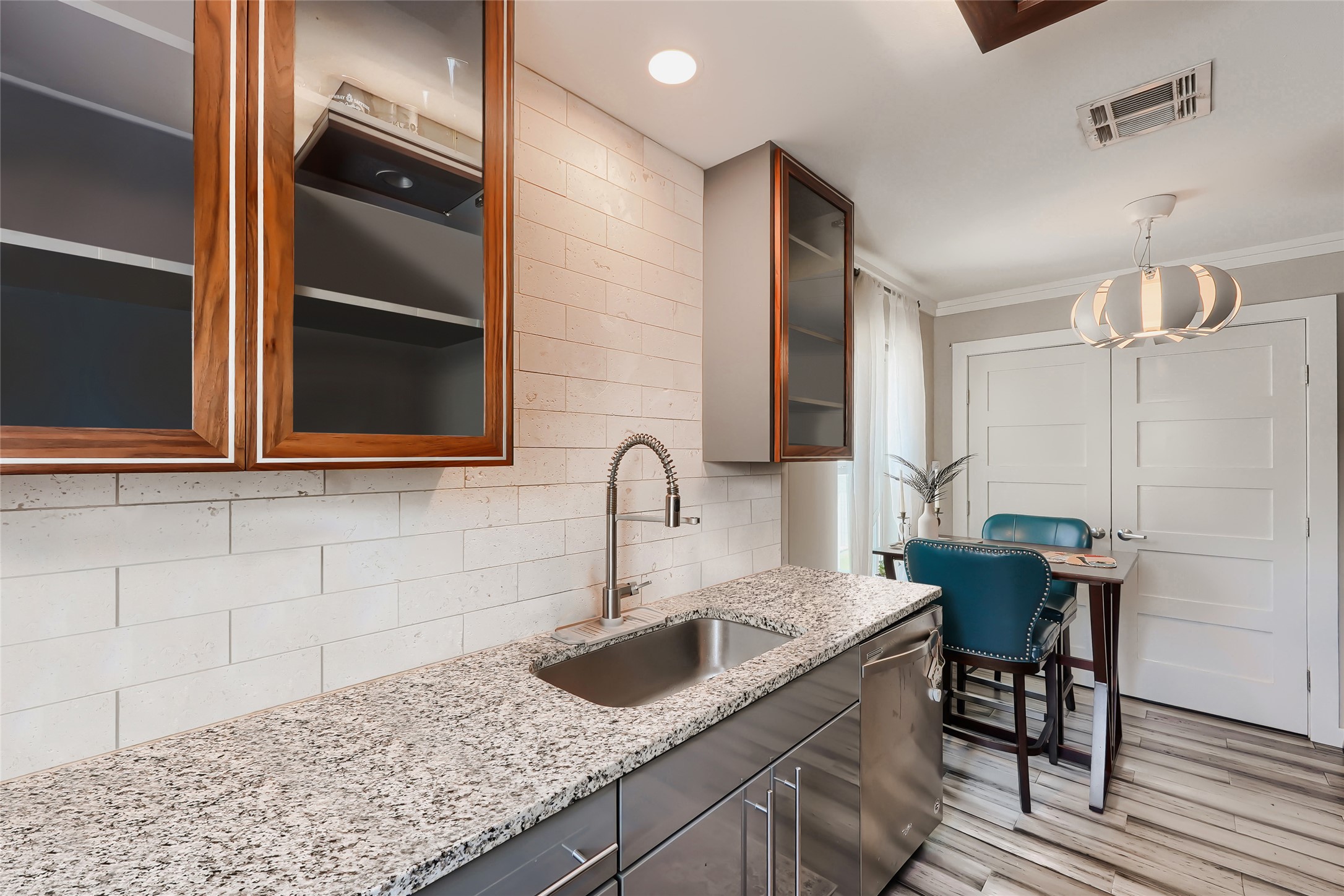 5707 Tracy Lynn Lane, Unit A Austin, TX 78721 - Photo 16 of 33 Kitchen featuring glass insert cabinets, light stone counters, backsplash, light wood finished floors, and dishwasher