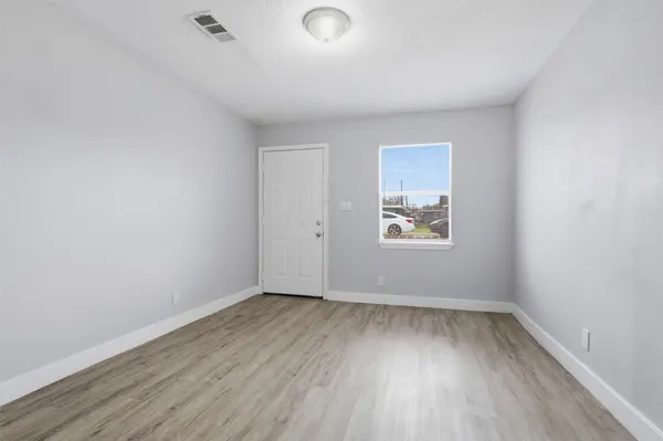 an empty room with wooden floor and windows