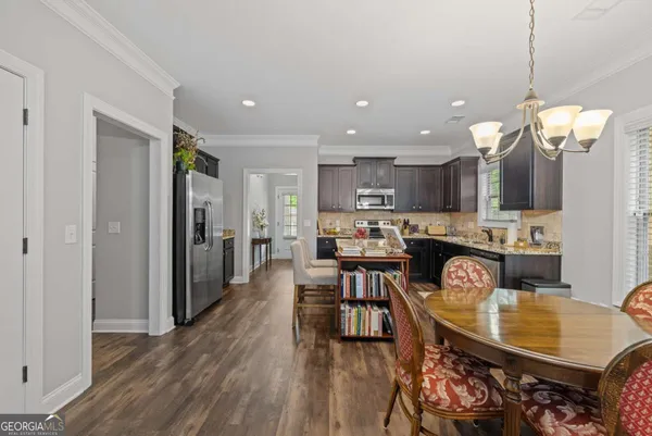 a kitchen with stainless steel appliances granite countertop a stove top oven a sink dishwasher and a refrigerator with wooden floor