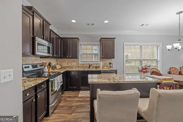 a kitchen with stainless steel appliances kitchen island granite countertop a kitchen island a stove and a dining table